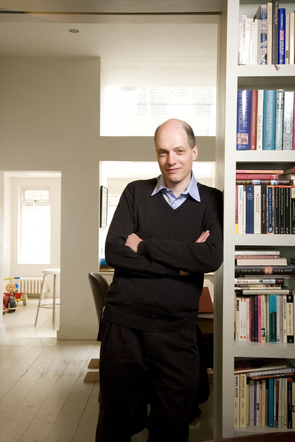 Image may contain Alain de Botton Furniture Shelf Bookcase Human Person Suit Coat Clothing Overcoat and Apparel