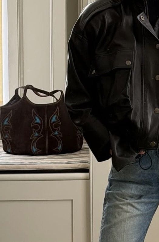 Alexa Chung con vaqueros, bolso de ante y chaqueta de piel.